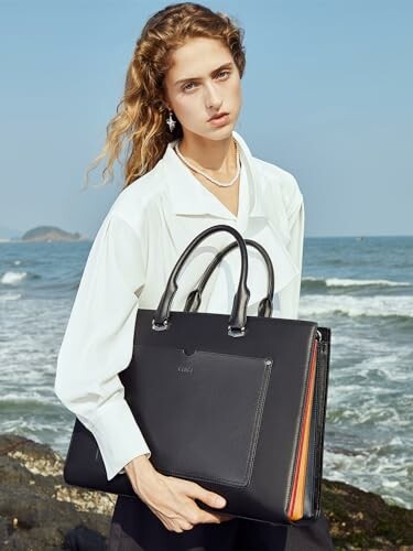 Woman holding a black handbag at the beach